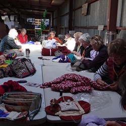 Ladies sewing BOG logos onto the rugs.